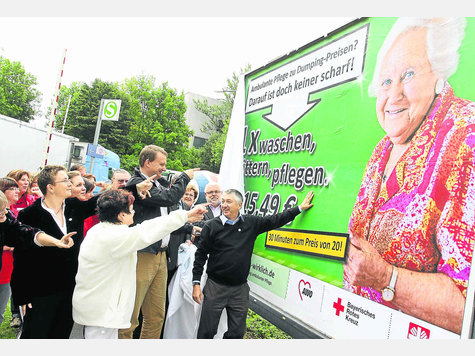 Mit diesen Plakaten k&auml;mpft die AWO f&uuml;r eine angemessene Verg&uuml;tung ambulanter Pflege. Oskar Krahmer (rechts) enth&uuml;llte das Plakat am Dachauer Bahnhof. foto: hab