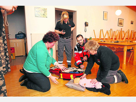 Simulation der Erstversorgung eines vom Wickeltisch gefallenen Kleinkindes durch die &bdquo;Helfer vor Ort&ldquo; Karin Hirschvogel (rechts) und Karo Schmidt (stehend). &bdquo;&Uuml;bungsmutter&ldquo; Gabi Sch&auml;ller (links) spielt dabei immer neue Situationen ein, Leiter Thomas Zimmer beobachtet das Szenario und beurteilt die T&auml;tigkeiten.