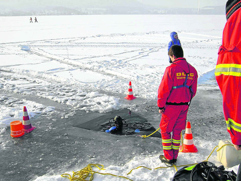 Durch ein kleine Loch stiegen die Taucher der DLRG in die Fluten des Tegernsees hinab. Derweil spazierten Menschen unbek&uuml;mmert quer &uuml;ber den See. Foto: KN