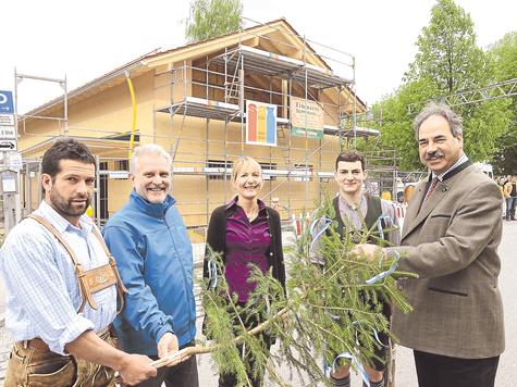 Hoch den Baum: (v.l.) Zimmermeister Sepp Mayr, Pfarrer Wolfgang D&ouml;rrich, stellvertretende Leiterin des Kindergartens Hollerbusch Ursula Stacheter, Zimmerer Franz Holzer und B&uuml;rgermeister Josef H&ouml;&szlig; bei der Hebfeier f&uuml;r die neue Krippe. foto: tp
