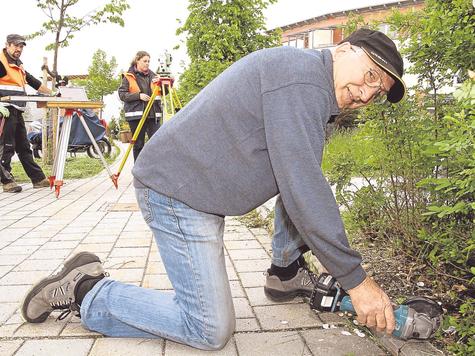 Feldgeschworener im Einsatz: Eberhard Schupp setzt mithilfe einer Flex eine Abmarkung, ein so genanntes Meiselzeichen, am Bordsteinrand von einem Flurgrundst&uuml;ck in der Balthasar-Graf-Stra&szlig;e. foto: dagmar rutt