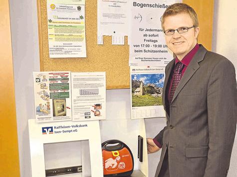 Repariert wieder an seinem alten Platz: der Defibrillator. Raiffeisenbank-Mitarbeiter Josef Obermeier demonstriert, dass man die Scheibe gar nicht einschlagen muss, um an das medizinische Ger&auml;t zu gelangen. foto: mot